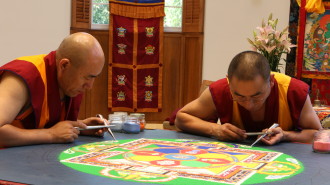 Tibetan Buddhist monks Gen Norbu (left) and Geshe Sangpo (right) construct a sand mandala for peace and healing.