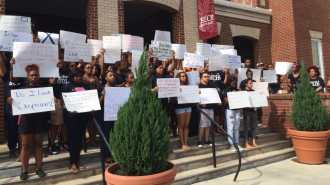 Student volunteers hold signs expressing their frustration with acts of bias and discrimination on Elon's campus