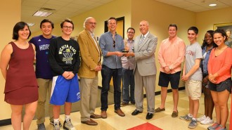 Mitch Pittman ’09 (center) presents Communications Dean Paul Parsons with one of his Emmy Award statues in April 2016.