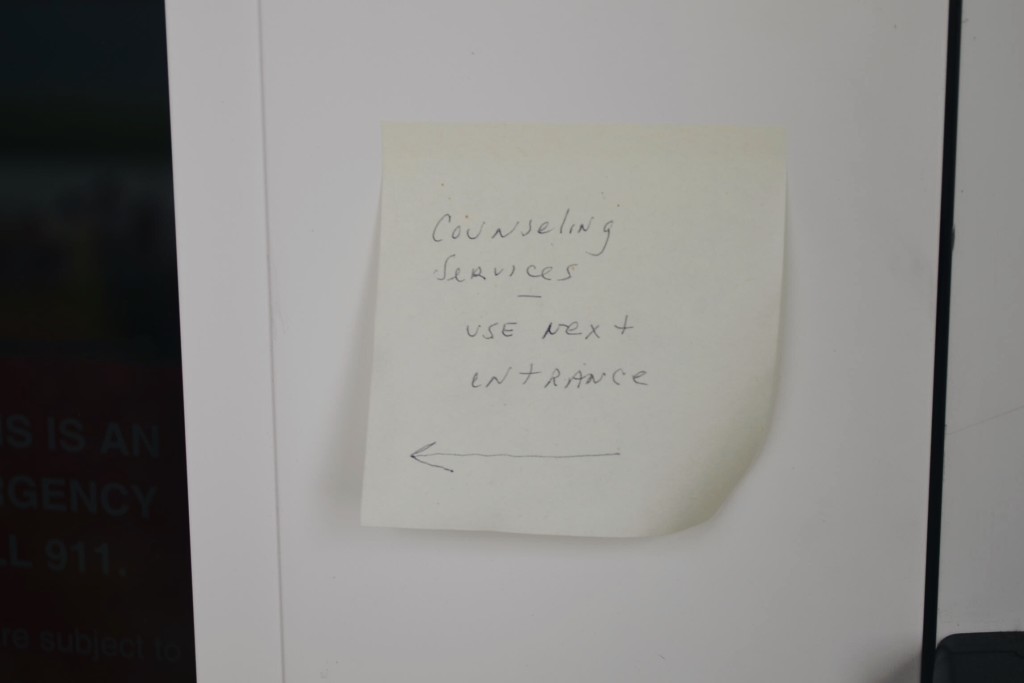 A post-it note on the Ellington Center’s main entrance. The text reads: “Counseling Services — use next entrance.” Photo by Jane Seidel